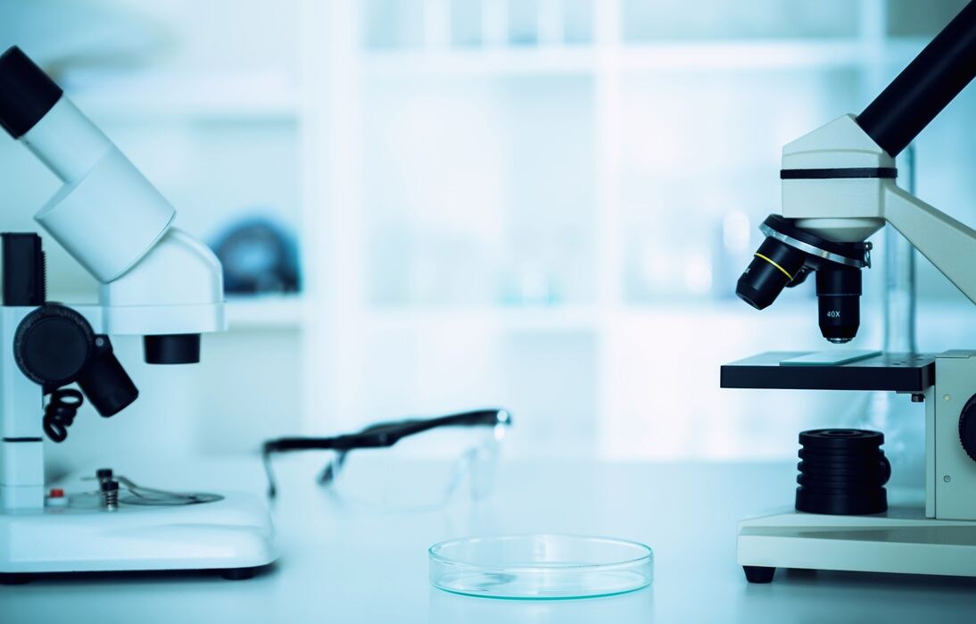Analyst at a microscope reviewing a prepared slide — UK occupational hygiene laboratory